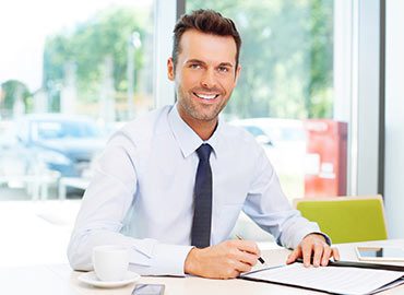 person11 Professional man in white shirt and tie smiling at desk with laptop