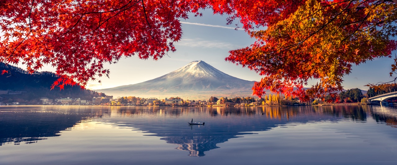 Colorful Autumn Season and Mountain Fuji with morning fog and red leaves at lake Kawaguchiko is one of the best places in Japan Mount Fuji snow-capped peak reflected in calm lake framed by vibrant red autumn maple leaves