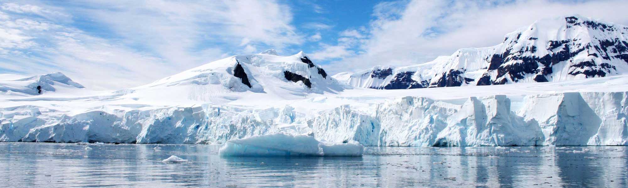 Antarctica-10 Snow-covered Antarctic mountains and glaciers with icebergs floating in blue water