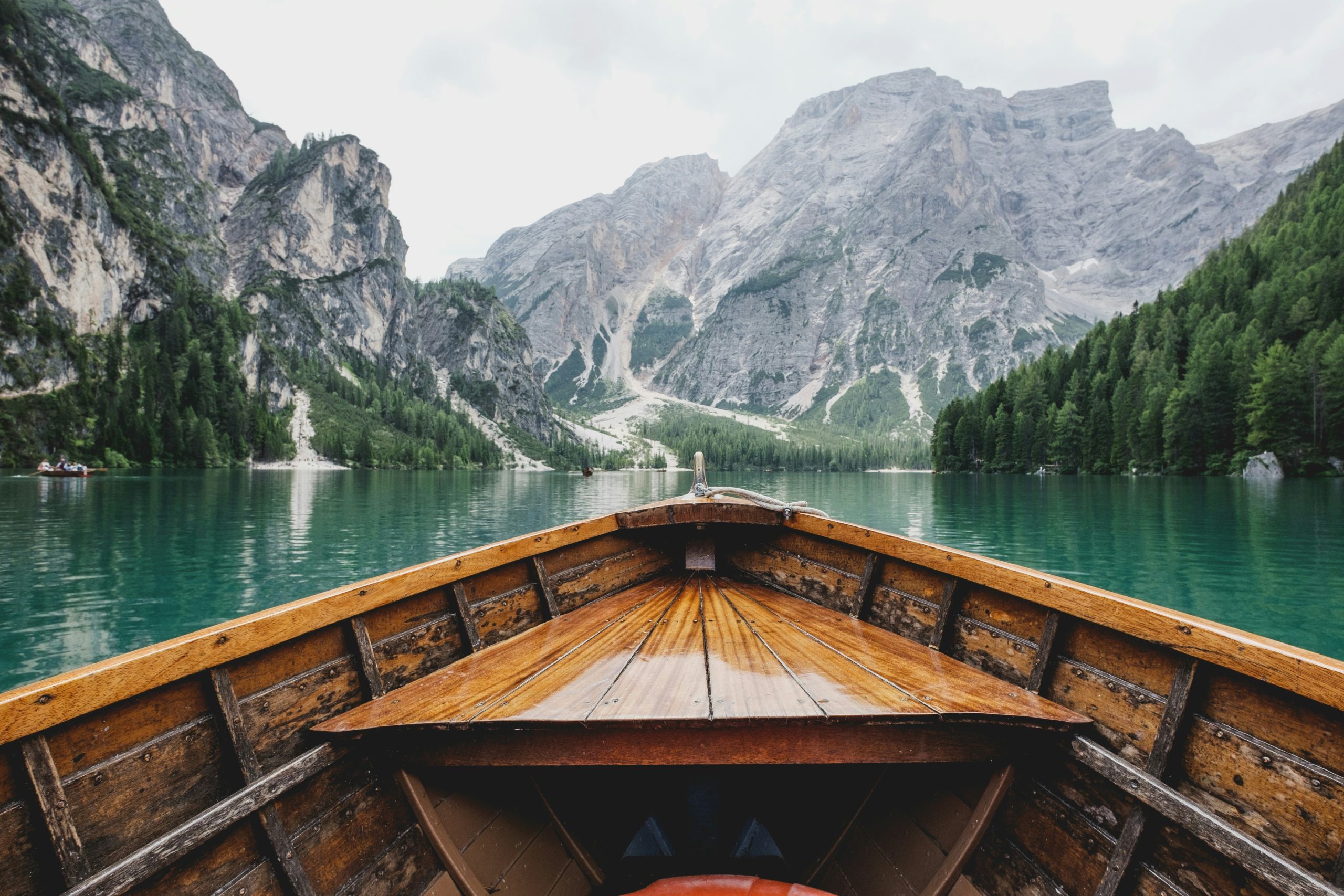 cherish the beauty Wooden boat bow on turquoise alpine lake surrounded by steep rocky mountains and pine forests