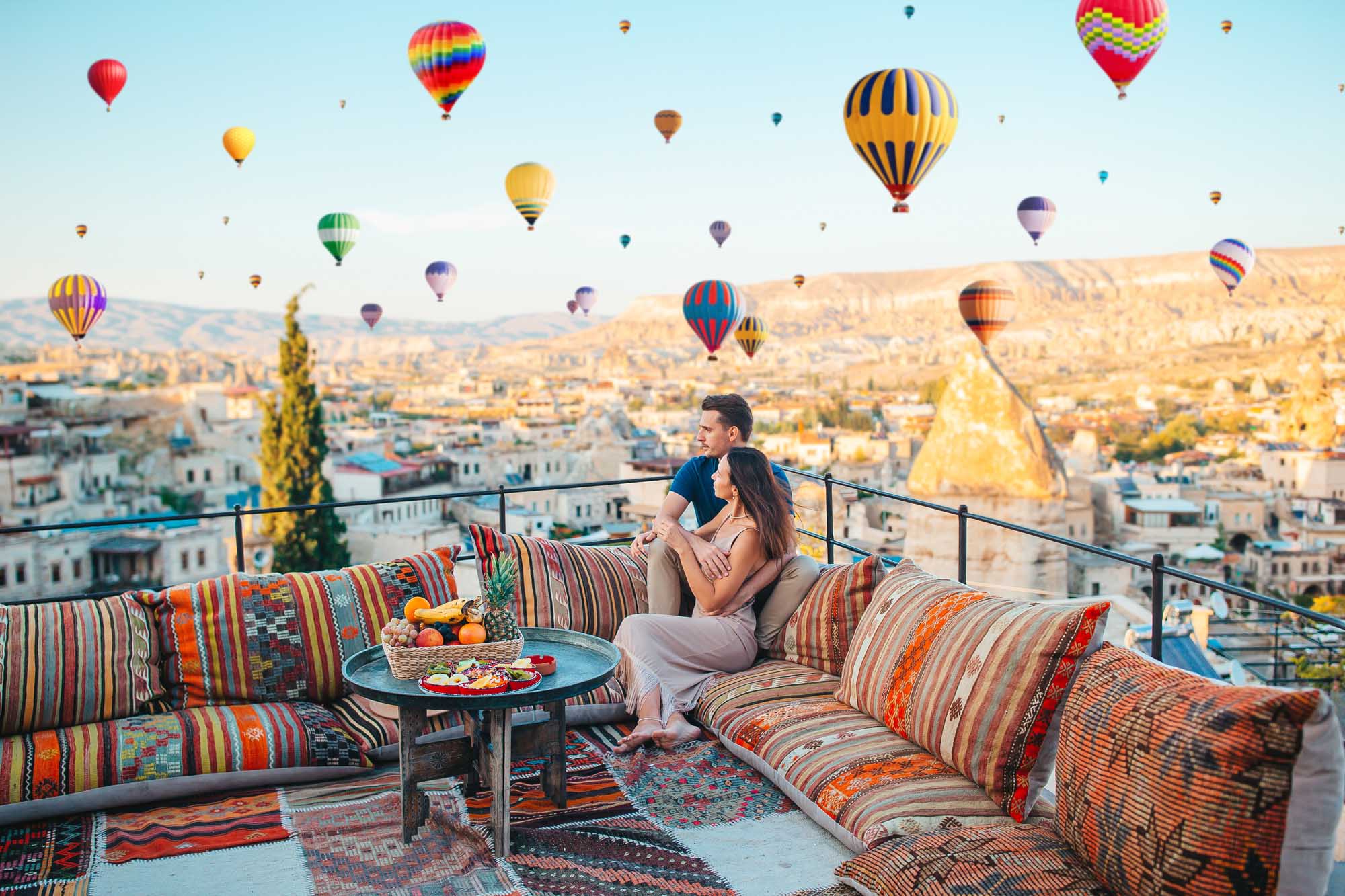 A romantic couple sits on a traditional cushioned seating area with colorful striped pillows