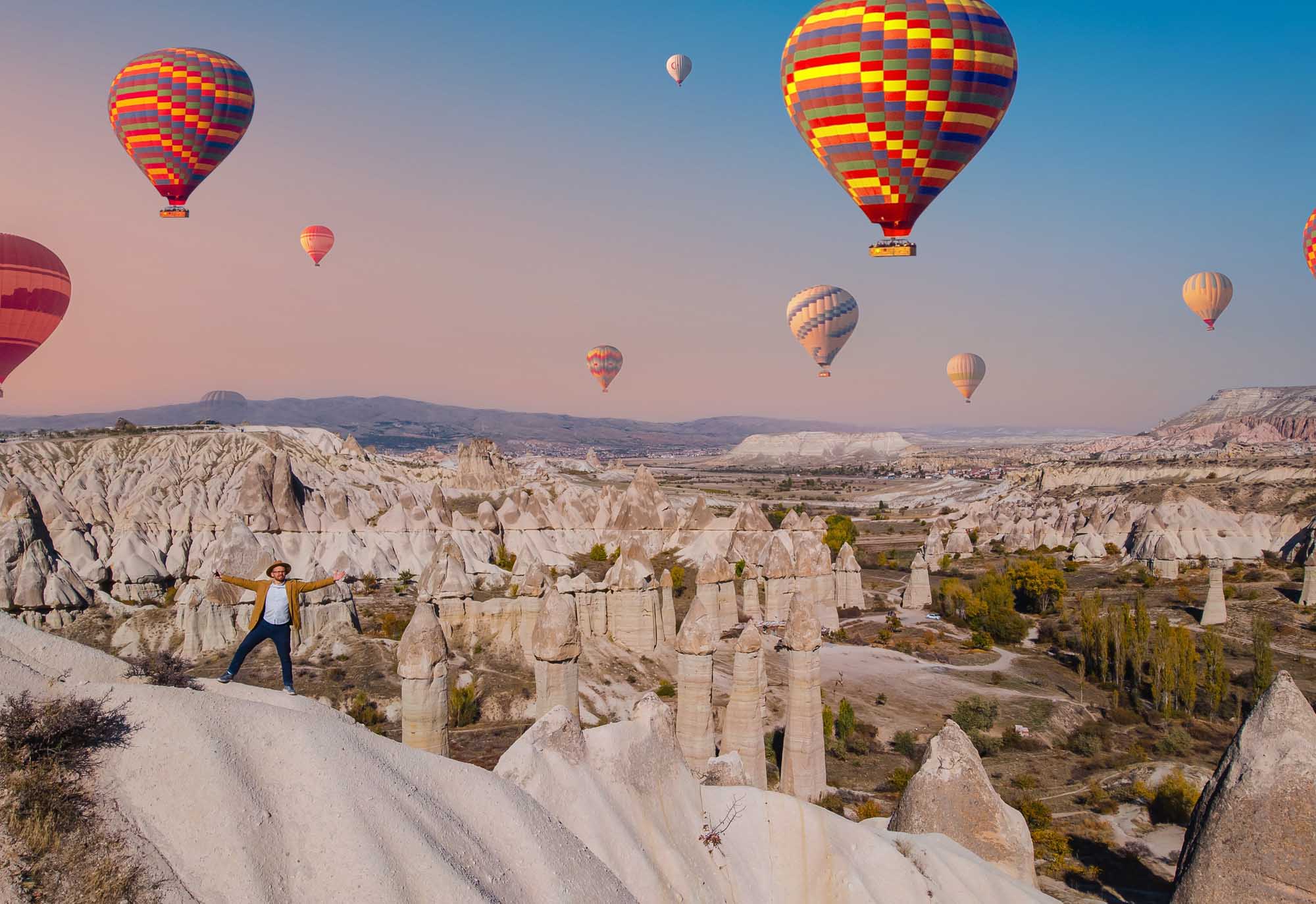 A stunning aerial view of colorful hot air balloons floating above the distinctive stone pillars