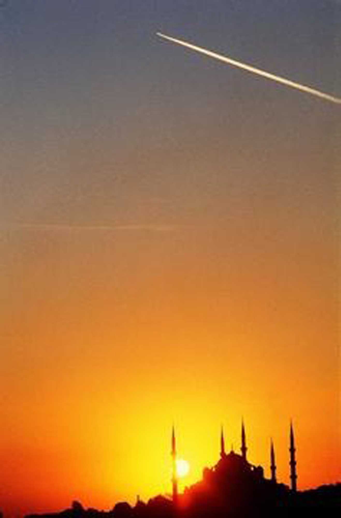 A stunning sunset photograph capturing the silhouette of a mosque with distinctive minarets against